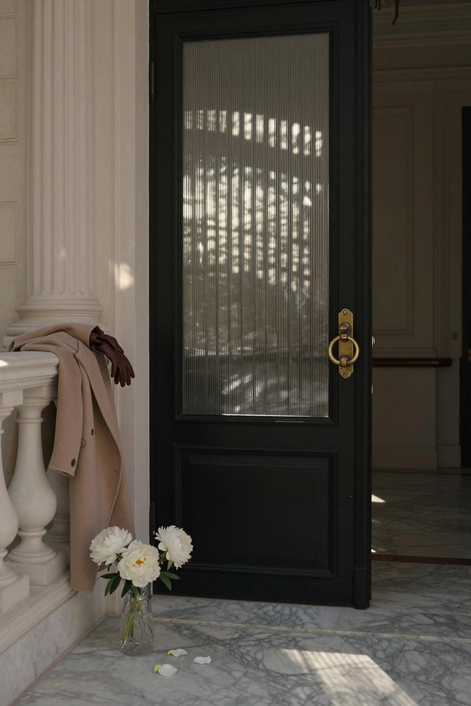 black matte-lacquered door with vertical reeded glass panels in Parisian penthouse entry with marble floors and brass knocker