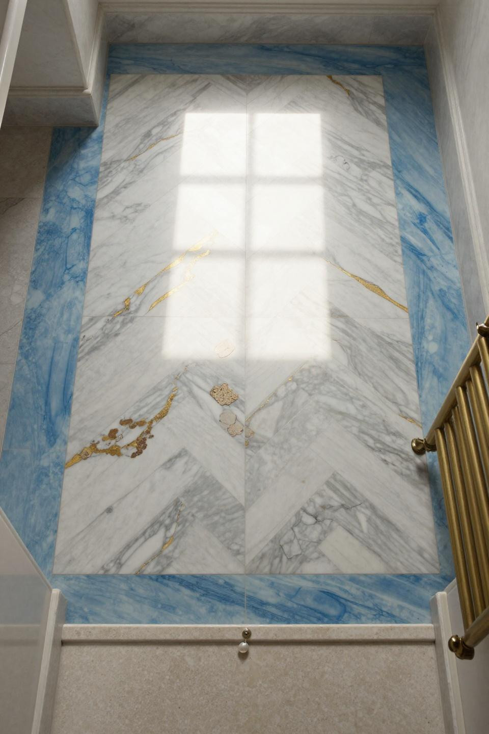 bathroom flooring ideas with chevron laid calacatta marble and dramatic gold veining bisected by glacier blue venetian plaster stripe