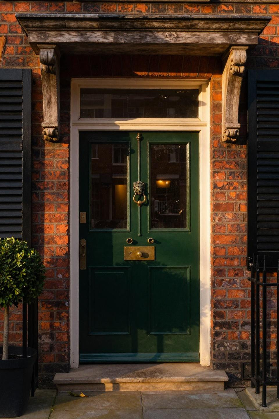 deep forest green lacquered dutch door with divided sections and brass lion knocker on red brick kensington townhouse