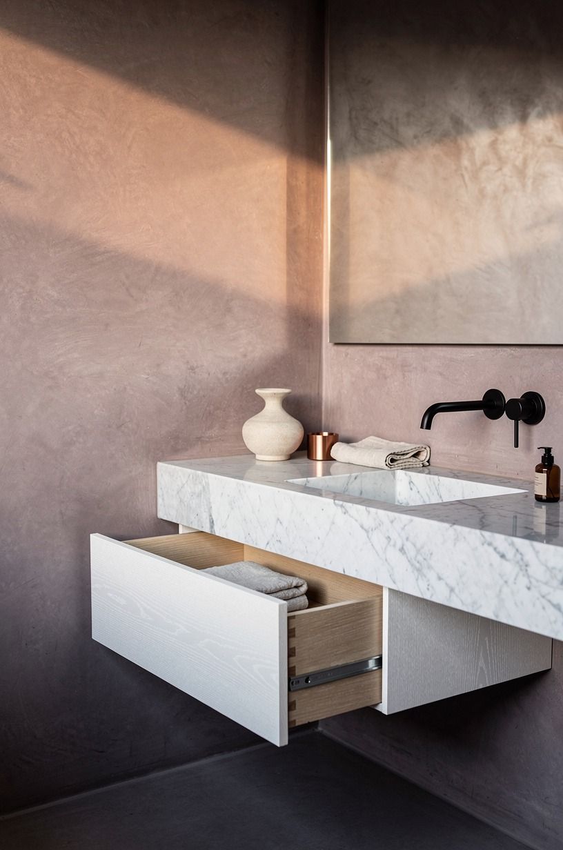 Layer clay-toned plaster around matte black taps